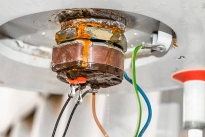 closeup of a corroded and leaking water heater